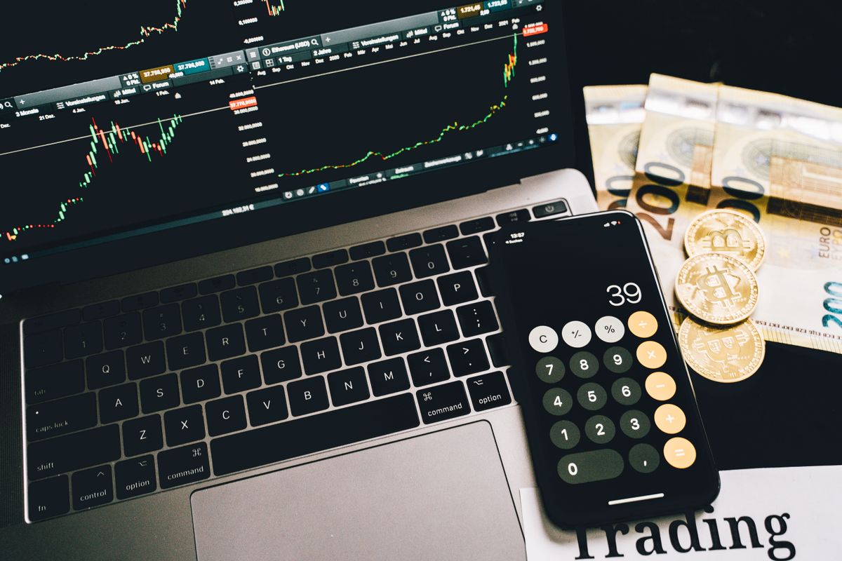 Calculadora, gráficos financieros en laptop y billetes que ilustran la planificación del presupuesto de capacitación corporativa